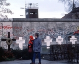 twee mensen lopen langs graven gesneuvelde vluchtelingen bij Berlinse muur