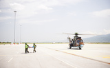 Helikopter op het vliegveld met 2 piloten die een brancard dragen