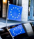 The miniature of the European flag and its reflection on the bonnet of a car