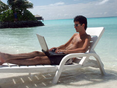 Man aan laptop op het strand