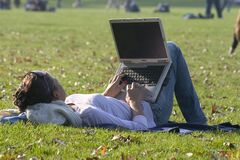 Vrouw ligt op het gras met laptop