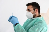 Een man met mondkapje heeft een injectiespuit in zijn hand